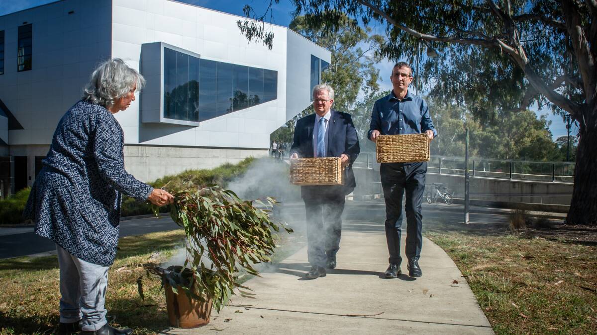 Ngunnawal elder Matilda House conducts a smoking ceremony as ANU vice-chancellor Brian Schmidt and director of the John Curtin Medical school Graham Mann carry the blood samples from the university. Picture: Karleen Minney