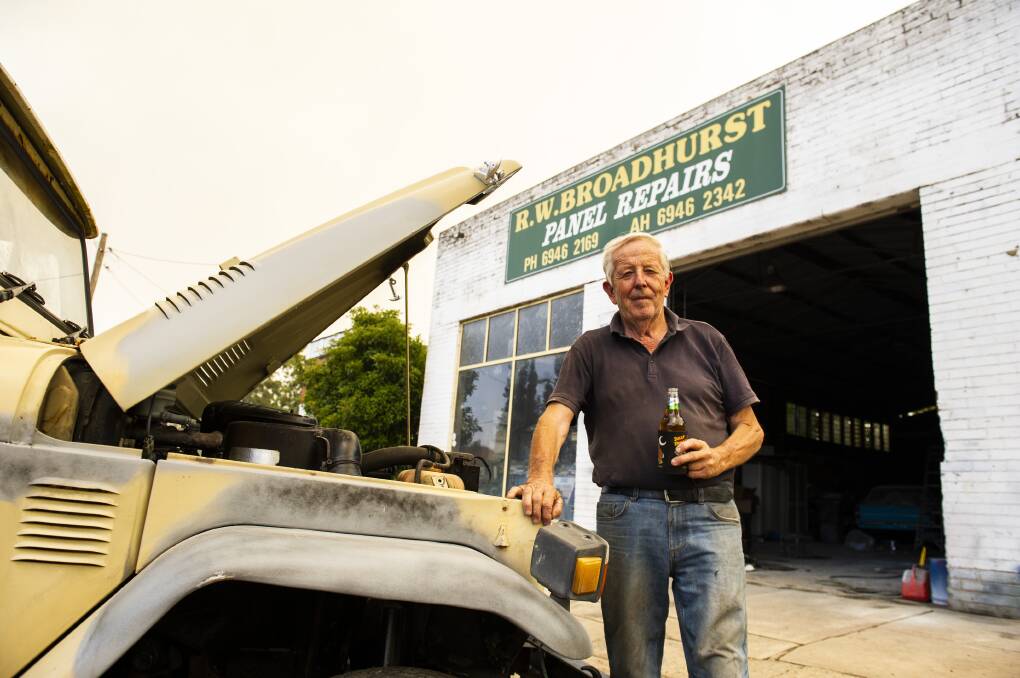 Adelong resident Bob Broadhurst, who owns R.W. Broadhurst Panel Repairs, has a beer outside his business as fires burn near the town, which was almost completely deserted. Picture: Dion Georgopoulos