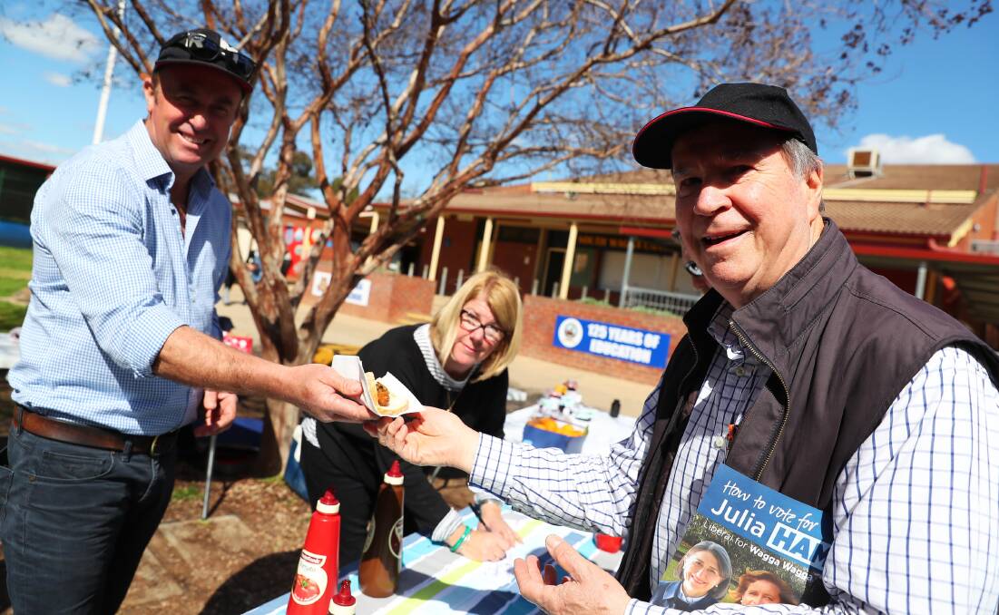 VOLUNTEERING: Dean Wilson ad Francine Owen sell Will Tuck a traditional election day "democracy sausage".