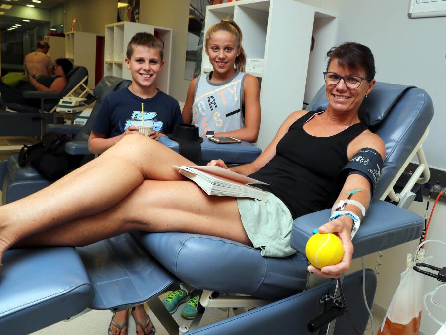 HELPING OUT: Ben, 10, and Emma Devries, 12, help mum Margaret with her drink while she makes her 174th donation. Picture: Les Smith