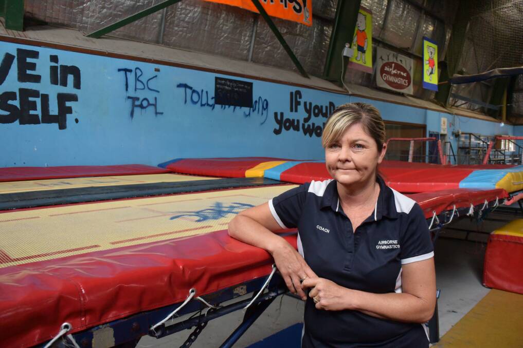 Lyndal Seymour stands next to one of the trampolines and a wall damaged by vandals at Airborne Gymnastics.