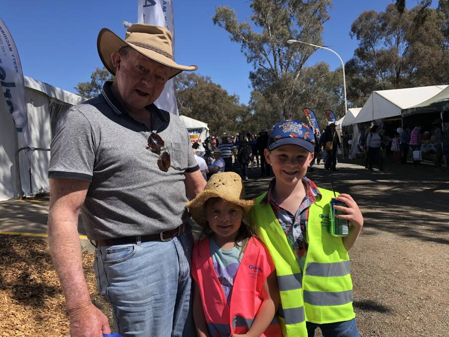 FARMERS TOYS: Former farmer Jim Perry from Howlong stands alongside his grandchildren Layla Burkenshaw, 4, and Leroy Burkenshaw, 6 at day one of the Henty Fields Day and said there's a 'smorgasbord' of options on offer. 
