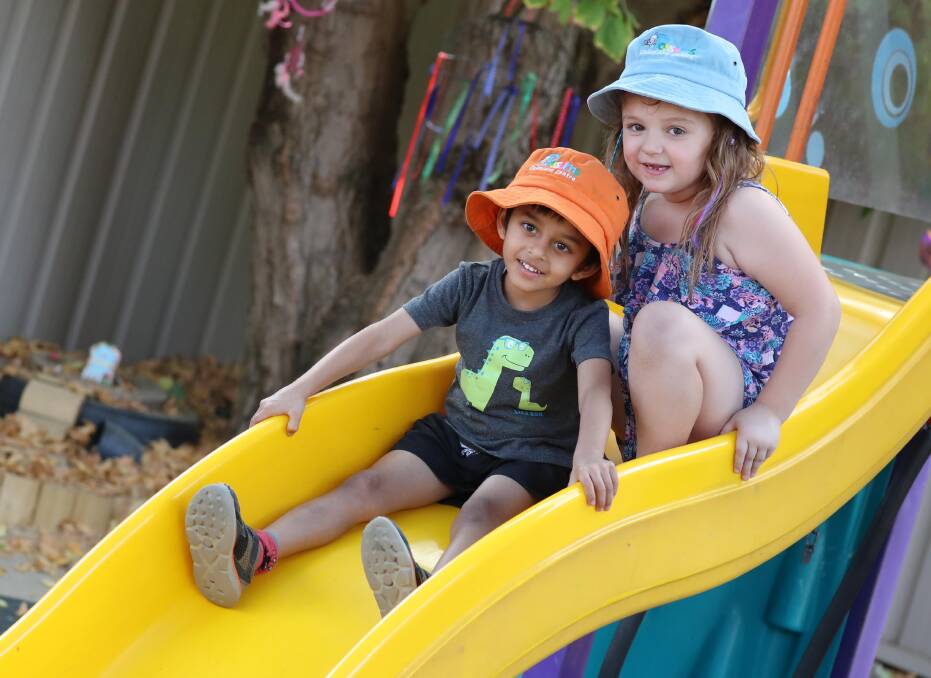 BUDDIES: Peyton-Grace Walsh, 5, and Advit Bhagwat, 4, are sliding down the big yellow slide at Possums Playground Occasional Child Care Centre. Picture: Les Smith