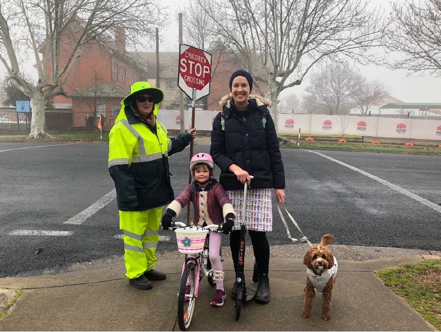 FAMILY CROSSING: Lollipop lady Jean McLoughlin guides Wagga mum Brenda Goodwin back from dropping off her child at Wagga Public School to start the trip to preschool with her daughter Elissa, 5, and dog Sonny. 