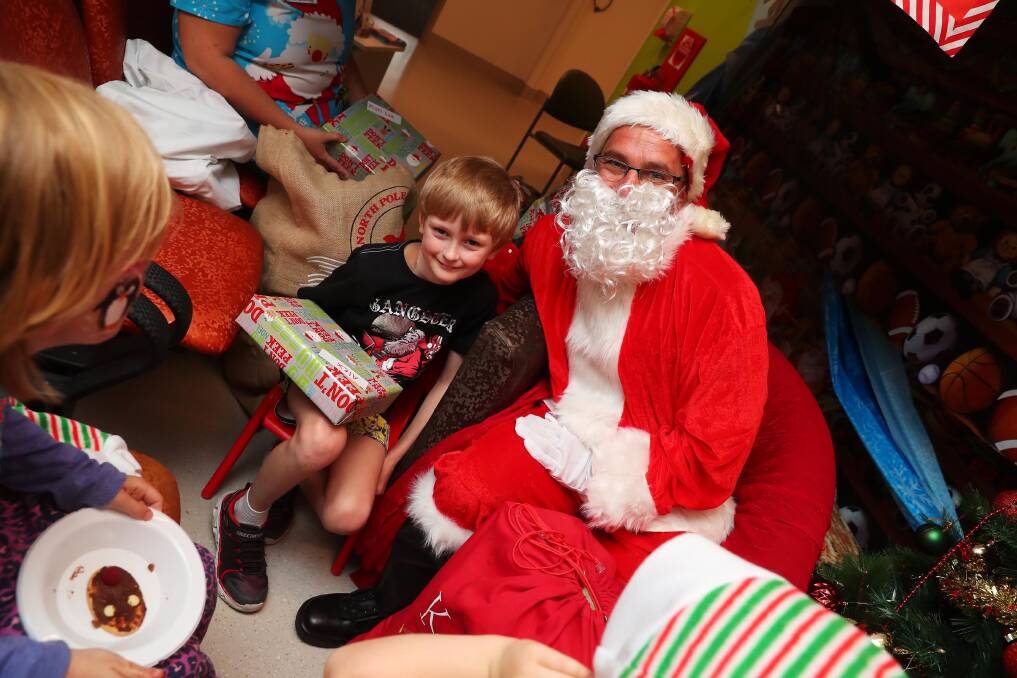 EARLY CHRISTMAS: Children and families at the Wagga Base Hospital had a surprise visit from Santa, Alex Balding, 8 receives the first present from Santa.
