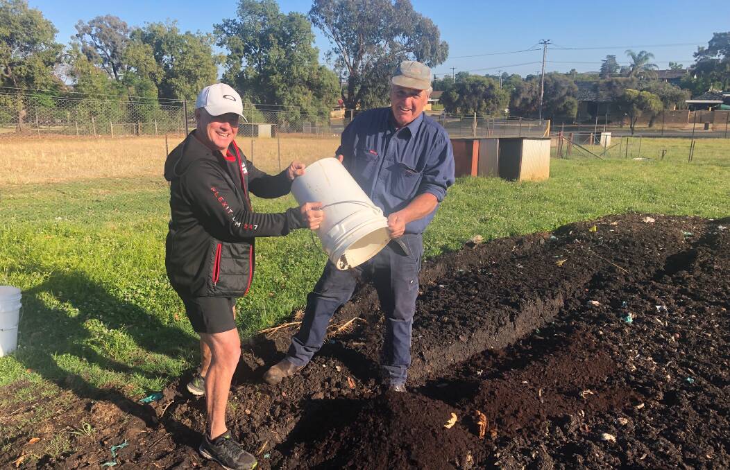TEAM EFFORT: Trail Street Coffee Shop owner Steve Vane dumps the coffee ground with the help of Mount Austin High School's farm manager Chris Lashbrook. Picture: Jess Whitty