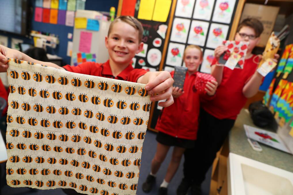 Cooper Henderson, Gemma McNaughton and Thane Sherwood are holding up their beeswax wraps they made last week to replace cling wrap for sustainable food packaging. 
