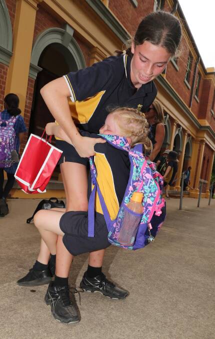 Maddie Brodie, 6, just can't let go of departing Year 6 student Immy Rodham. Picture: Les Smith
