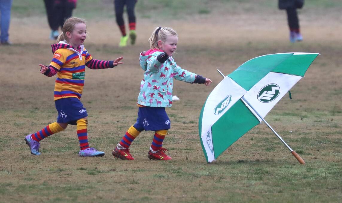 RUN LIKE THE WIND: Emily Morrow, 5, and Fleur Stalley, 4, chase umbrella at Wagga Crows Rugby Gala Day at Parramore Park. Picture: Les Smith