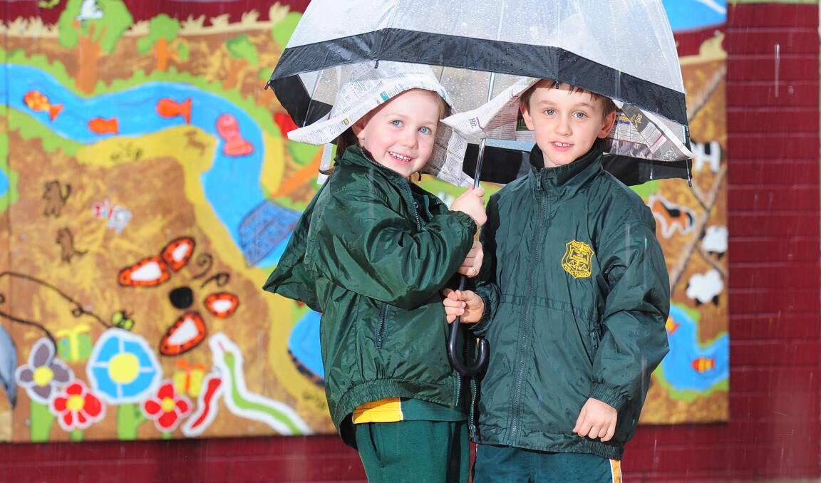RAINY DAYS: Five-year-old North Wagga students Georgia Whyte and Alexander Minehan stay dry on Friday. Picture: Kieren L Tilly.