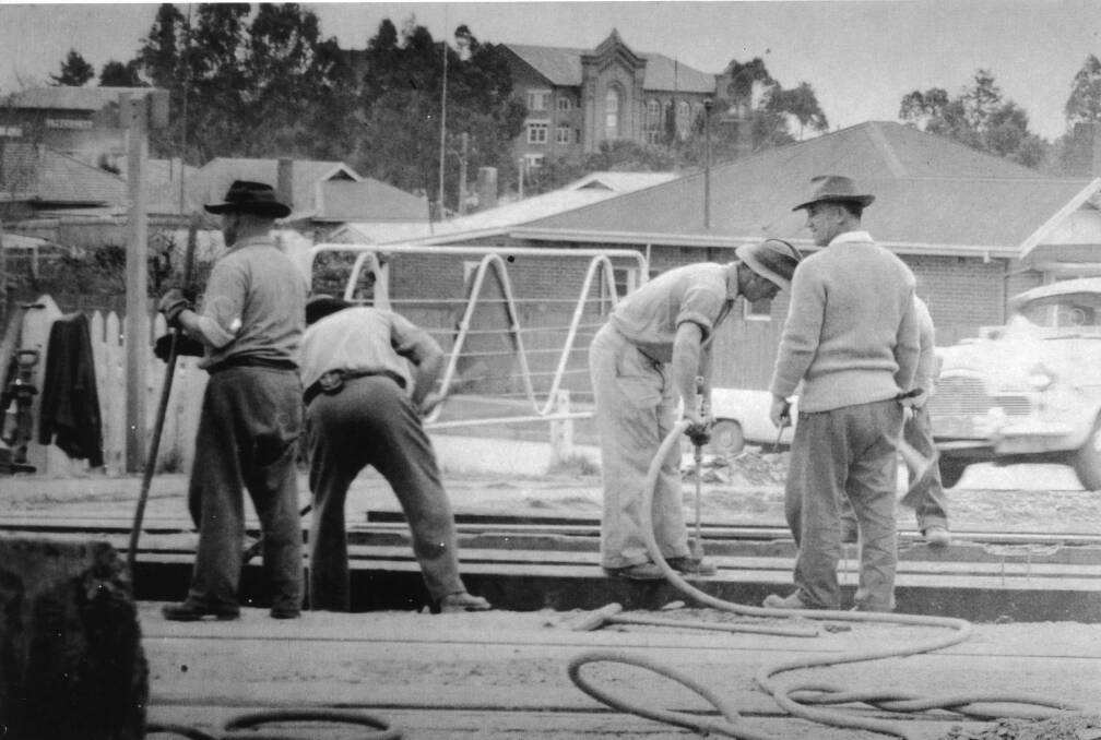 MOMENT: Workers at the Docker Street rail crossing. Notice the crossing gates and in the background Calvary Hospital. Picture: Lennon Collection CSURA RW1574.