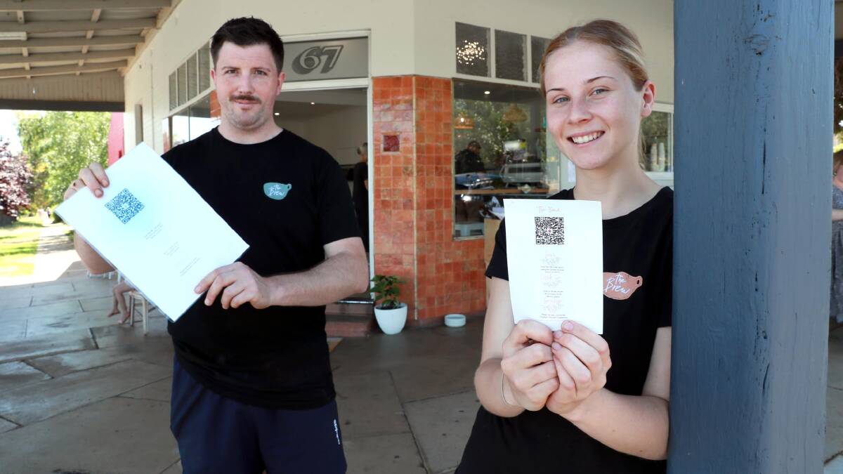 NEW NORM: The Brew manager Emily Podmore with barista Matthew Mangan and the QR codes scattered around the cafe since it first opened. Picture: Les Smith