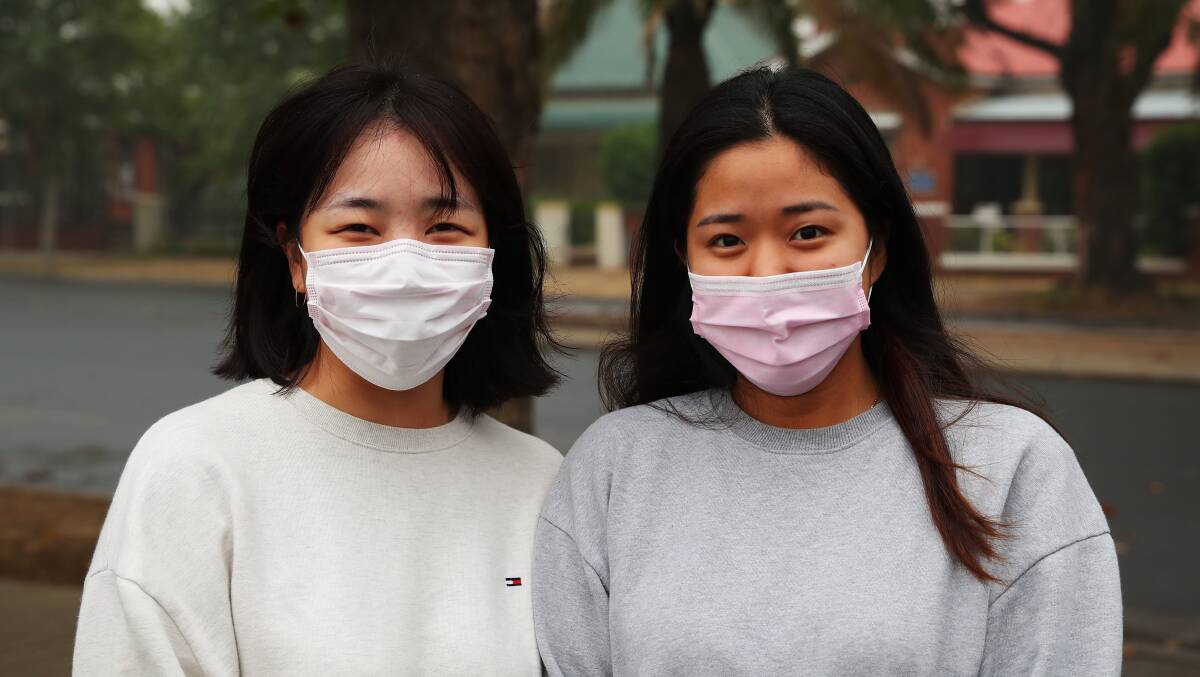 Korean travelers Mirim Kwon and Yurin Lee try to protect themselves from the hazardous smoke around Wagga in January.