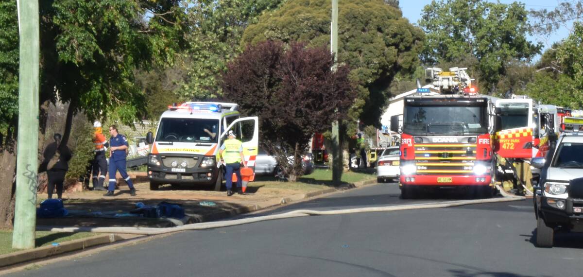 Paramedics respond at the home of a man who suffered a cardiac arrest across the road from a house fire in Tolland on Wednesday. The man later died in hospital.