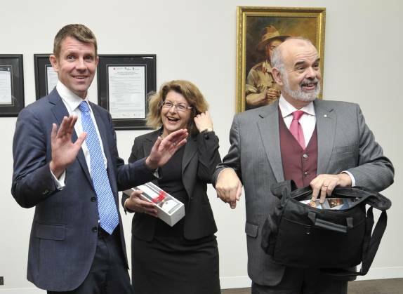 Then NSW premier Mike Baird in 2014 reacts to gifts presented by REROC chairman Paul Braybrooks (right), including a bottle of olive oil held by REROC executive officer Julie Briggs.