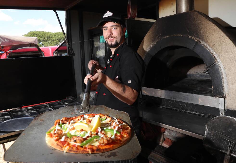 TRIAL DATE: Wagga's Woodfire Wagon owner Jay Vidler, who has taken part in the city's food truck trial, serves pizza from his vehicle oven.