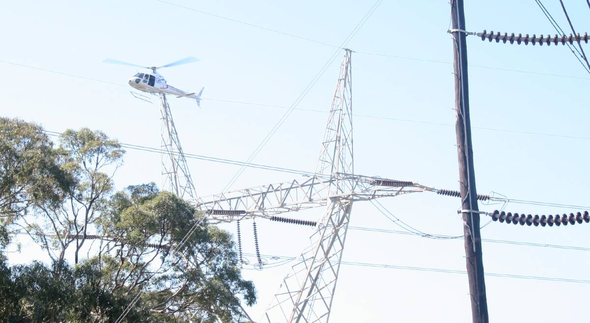 A TransGrid helicopter checks for faults on a high-voltage transmission line. NSW is one step closer to greater community consultations for new transmission line projects due to an amendment by Wagga MP Joe McGirr.