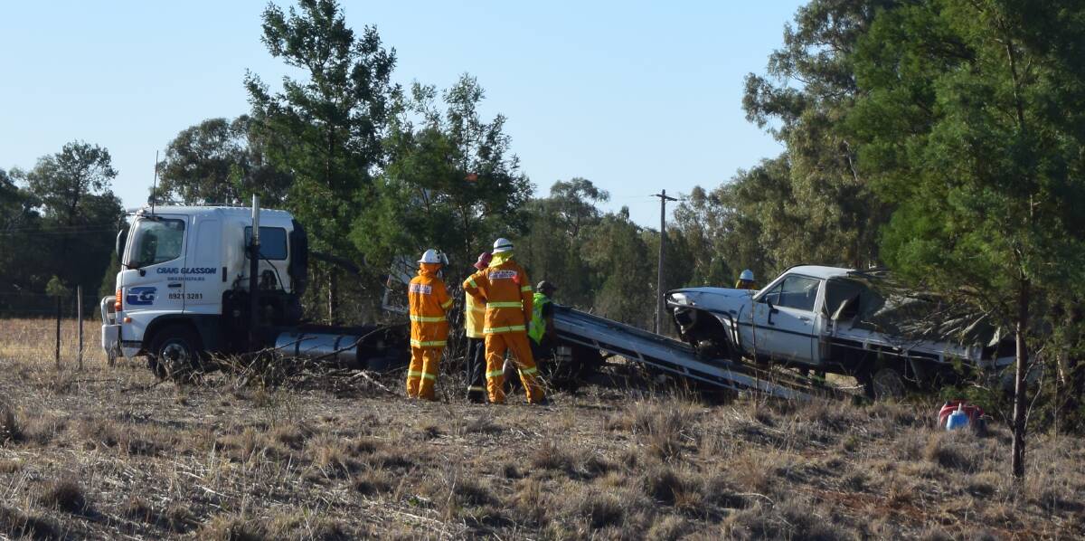 SAFETY FIRST: RFS crew members help with moving one of the utes involved in the crash onto a tow truck. Picture: Rex Martinich