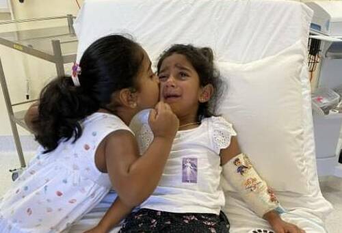 Kopika Muruguppan, age 6, comforts her sister Tharnicaa, aged 4, while receiving medical care in immigration detention.Picture: Home to Bilo campaign. 