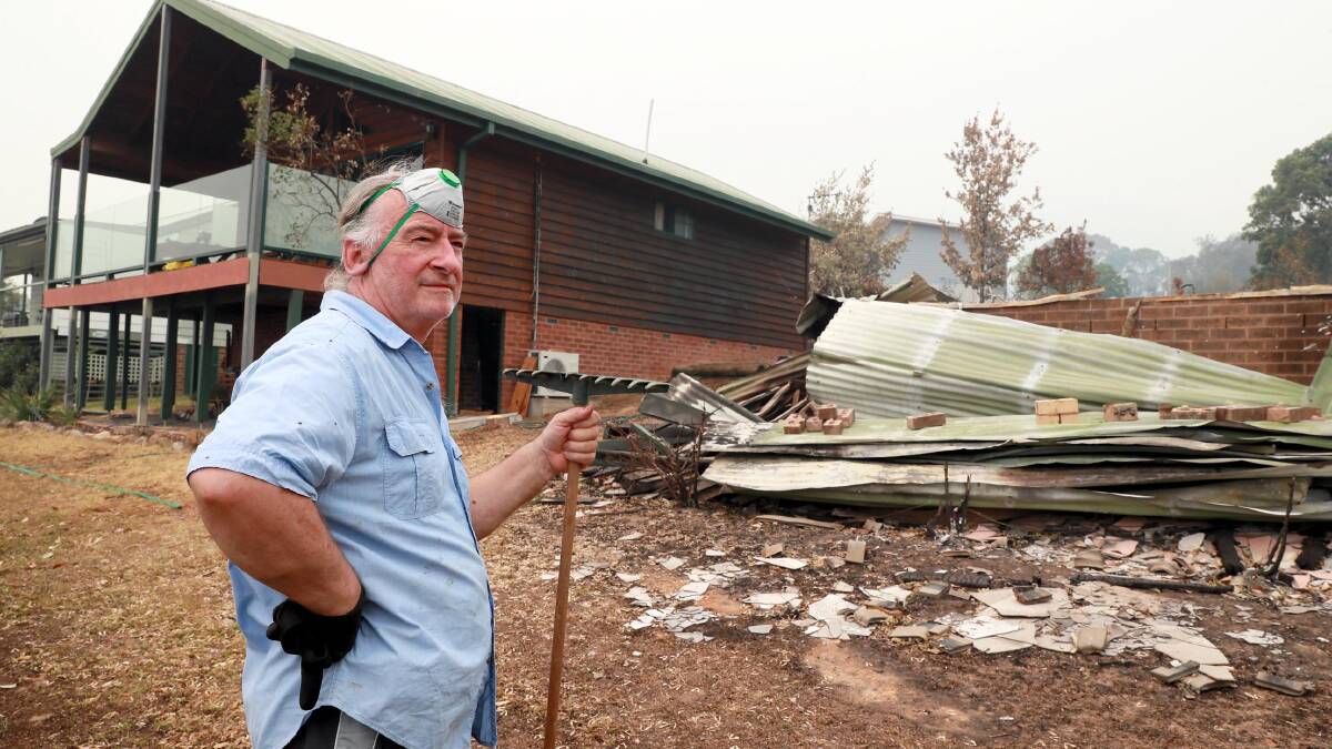 Dushan Ristevski cleans up in the aftermath of the Dunns Road fire at Talbingo. His Whitty Street Property was saved but his neighbour's house was razed to the ground