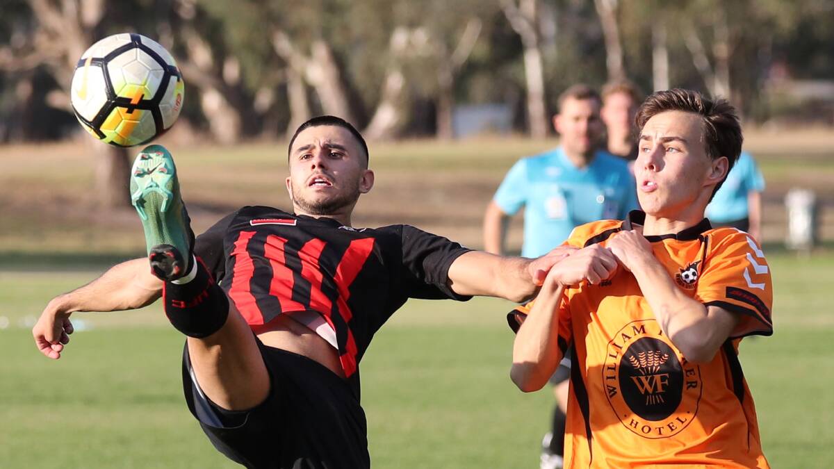 BICYCLE KICK: Anthony Trifogli (left) rocks back in an attempt to regain possession for Leeton against Wagga United. 