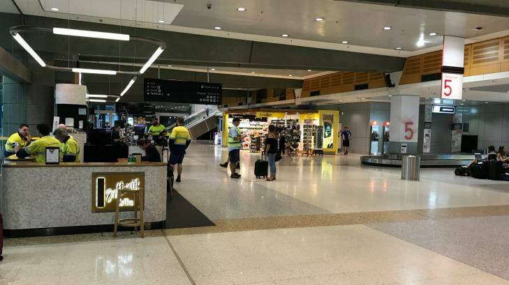 Qantas ground crews in a deserted domestic terminal, as a storm hits Sydney. Photo: Jenna Clarke