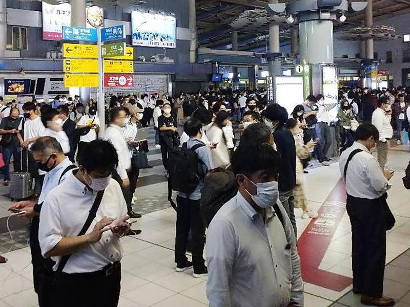 Passengers waited outside the entrance of a railway station after an earthquake shook Tokyo.