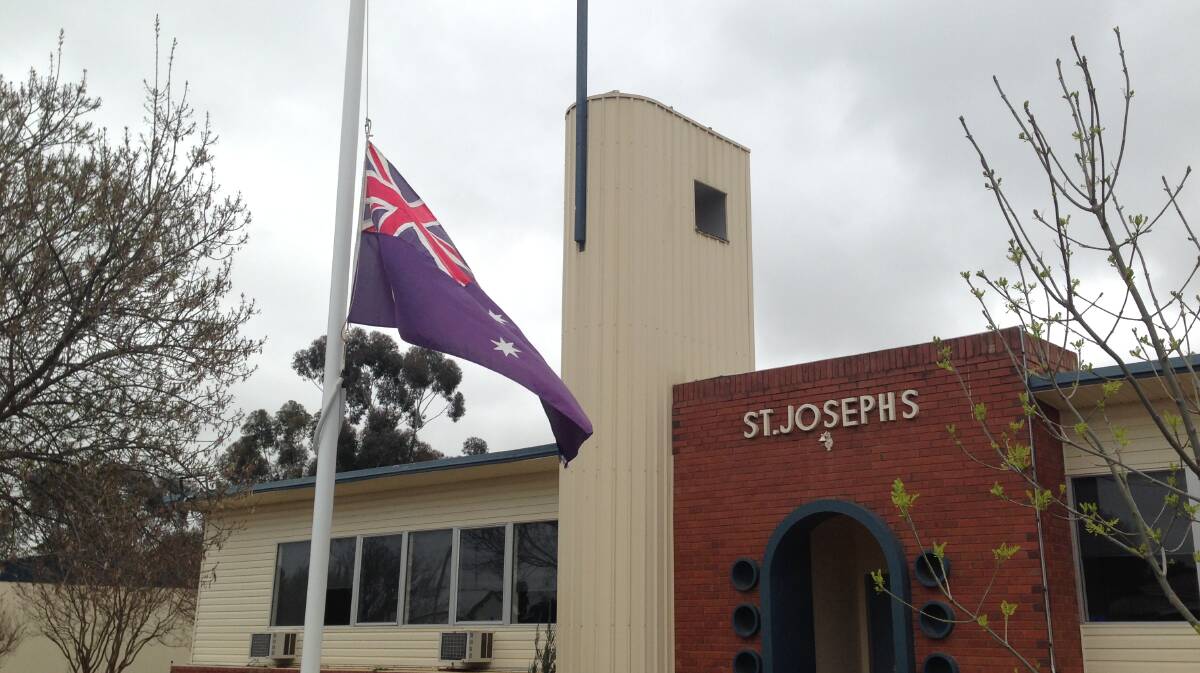 The Australian flag outside St Joseph's Catholic primary school in Lockhart  - which has an enrolment of just 74 - has flown at half mast since Wednesday morning as parents, teachers and students struggle to come to terms with the deaths of the Hunt family. Picture: Andrew Pearson