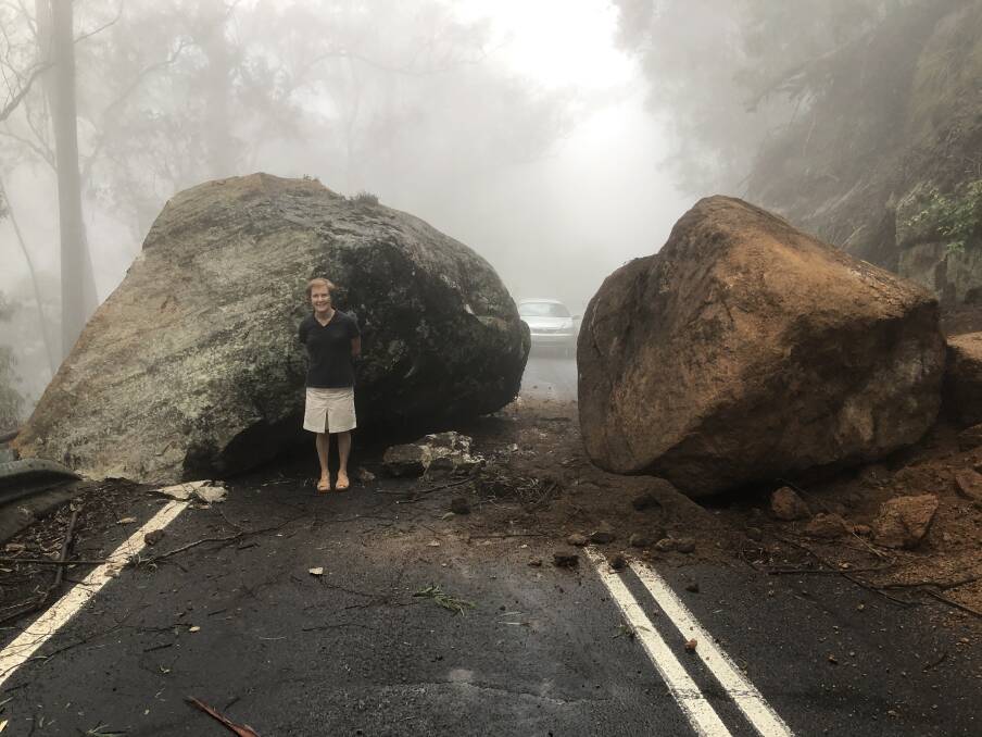 BIG DELAYS: Carolyn Butko with the two large boulders which rolled onto the Snowy Mountain Highway at Brown Mountain on Saturday afternoon. 