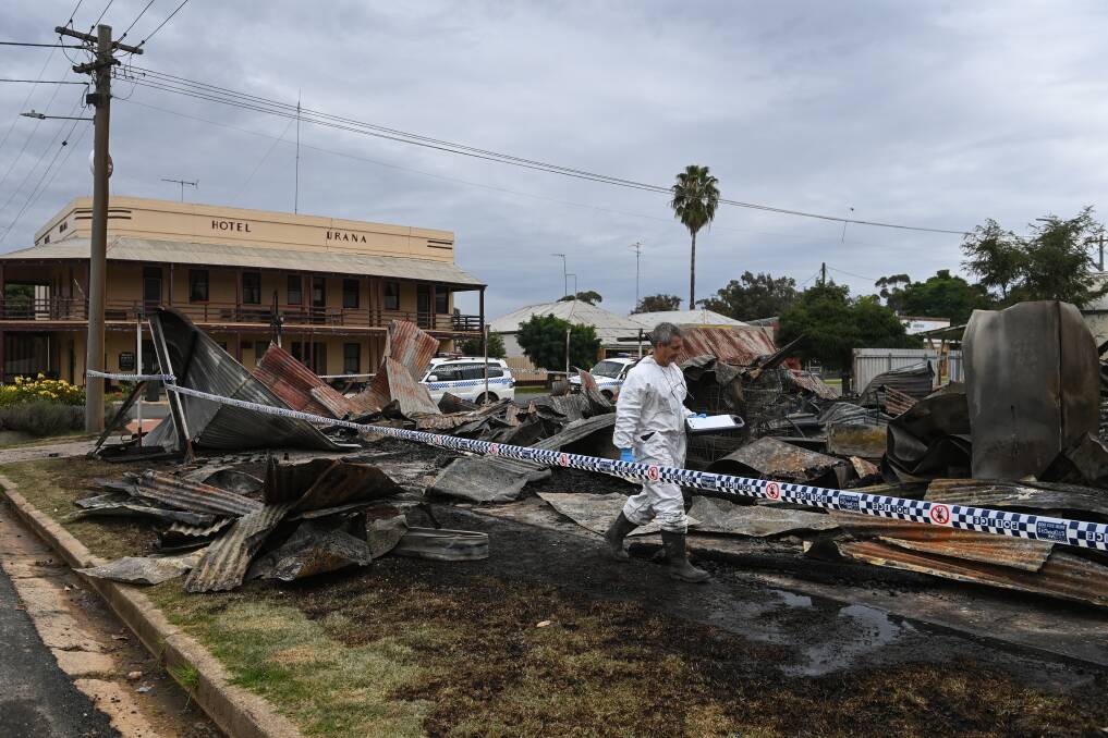 INVESTIGATION: A fire investigator searches through the flattened Urana business yesterday. Nearby resident Julie Barker thought the fire started in an area with chemicals and garden supplies. Picture: MARK JESSER