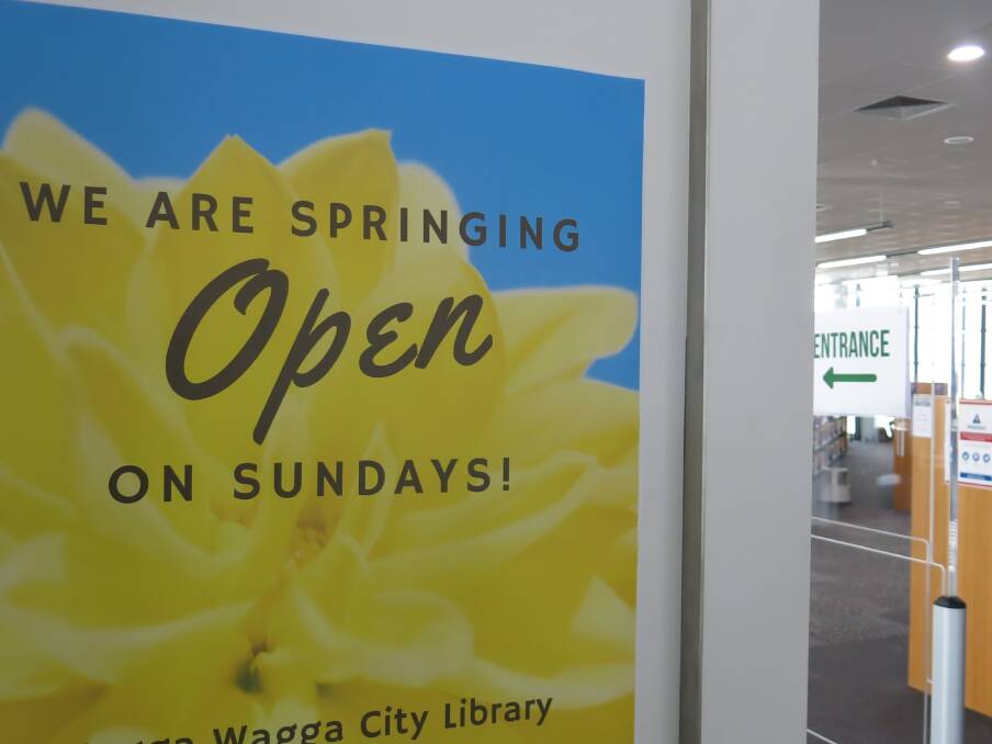 OPEN DOOR: A sign announcing the new Sunday hours invites library patrons through the open door.