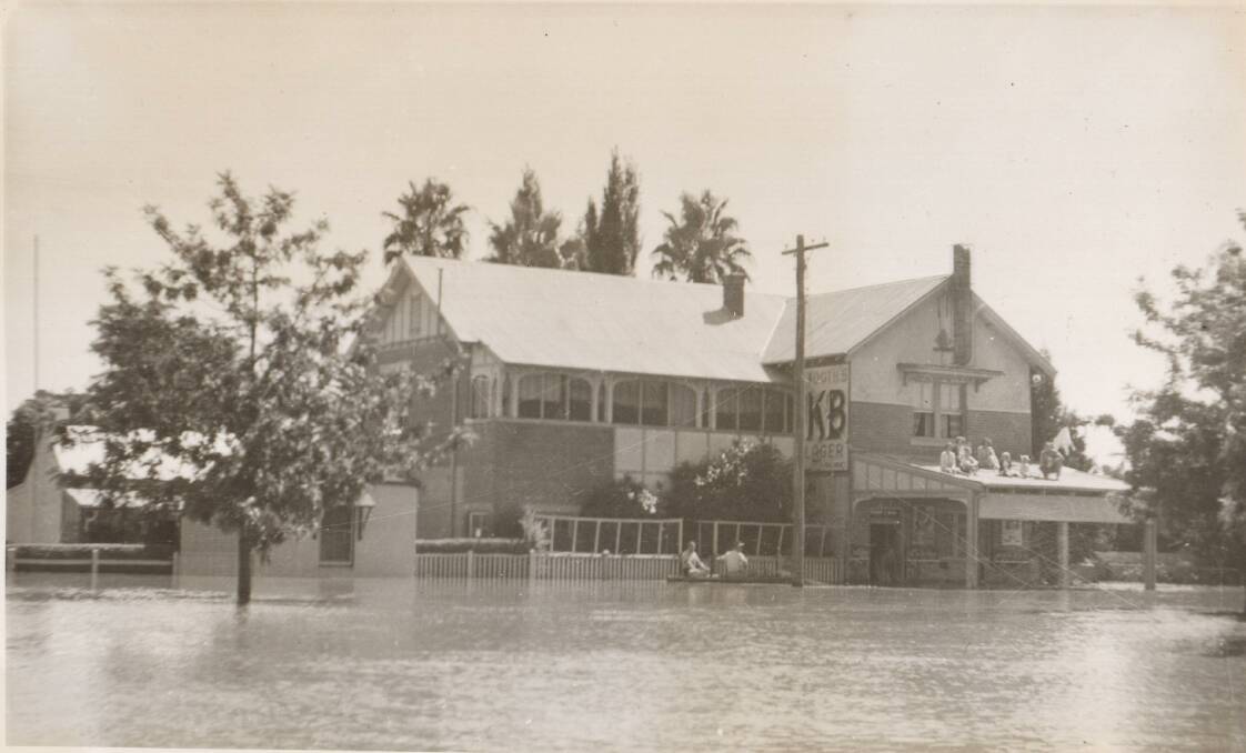 FLOODED: Leavers Hotel in North Wagga (now the Palm and Pawn Hotel) during a flood in the early 1950s. Seven people are stranded on the lower roof. Photo: Sherry Morris