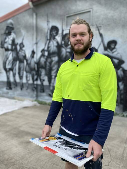 JOB WELL DONE: Adelaide-based artist Sam Brooks designed and painted the mural to capture Tarcutta's rich war history and the sacrifice made by those with ties to the town. Picture: Eastern Riverina Arts