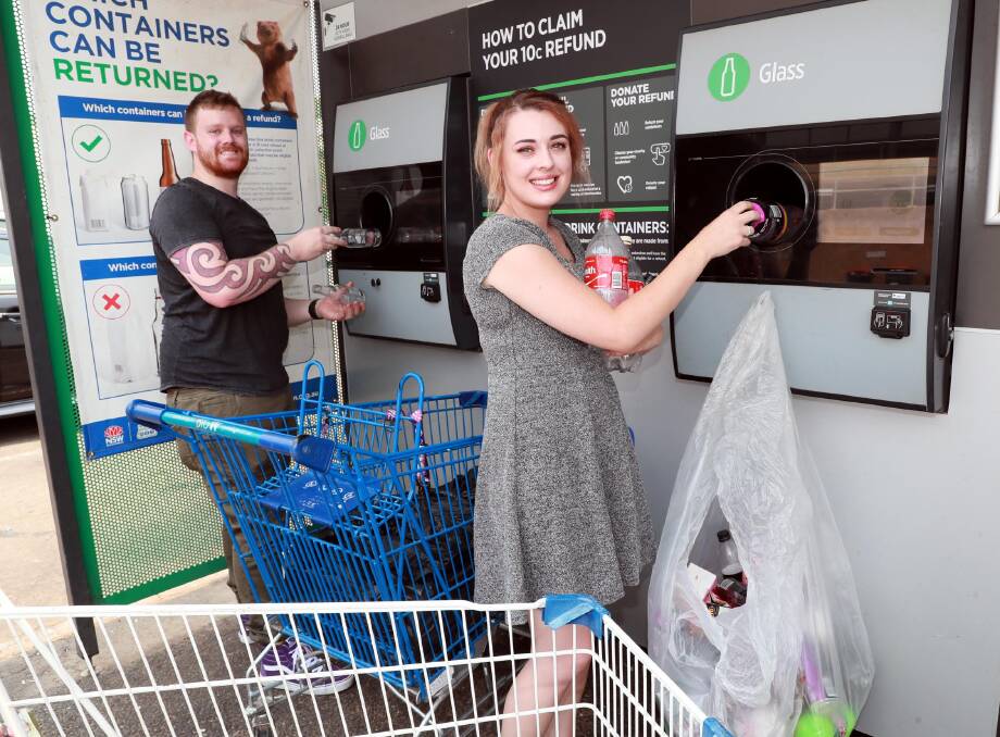 KIND GESTURE: Jacob Nealie helps Courtney Smith feed bottles through the Gurwood Street Return and Earn machine. Picture: Les Smith