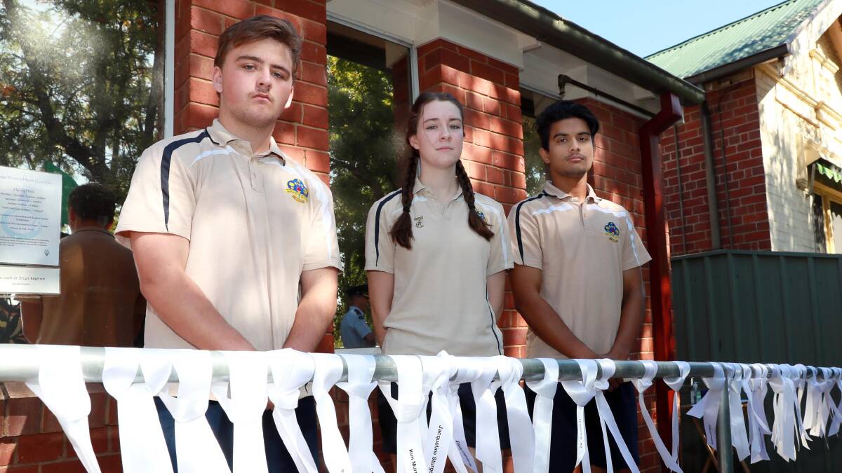 IN MEMORY: Kooringal High School Year 12 students Reilly Wauch-Smith, Chloe Hines and Aayan Bashar took part in the domestic violence acknowledgment ceremony, tying a white ribbon on the post for each victim. Picture: Les Smith