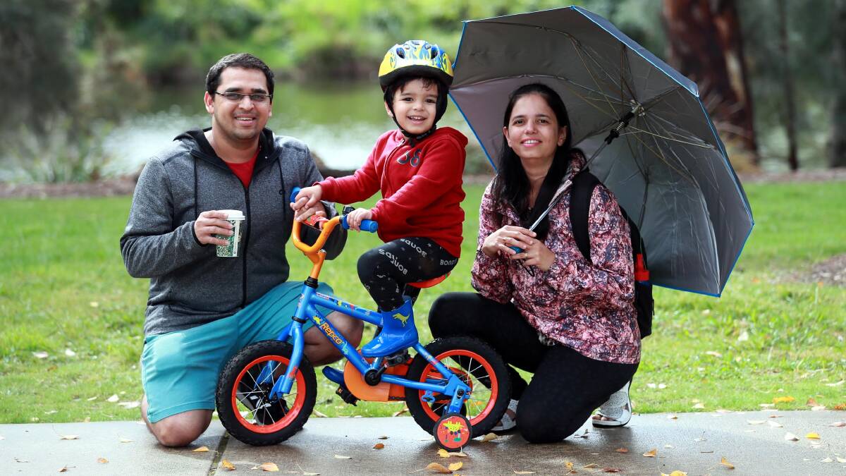 The Pendse family with Himanshu, 4-year-old Neel and Amruta don't mind getting a bit wet as they get their daily exercise in by Wollundry Lagoon. Picture: Les Smith