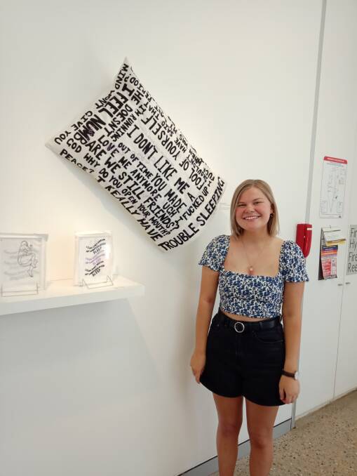 PROUD RESULT: Abbie Holbrook stands proud with her artwork on display, featuring a pillow lined with statements related to her anxieties. Picture: Contributed