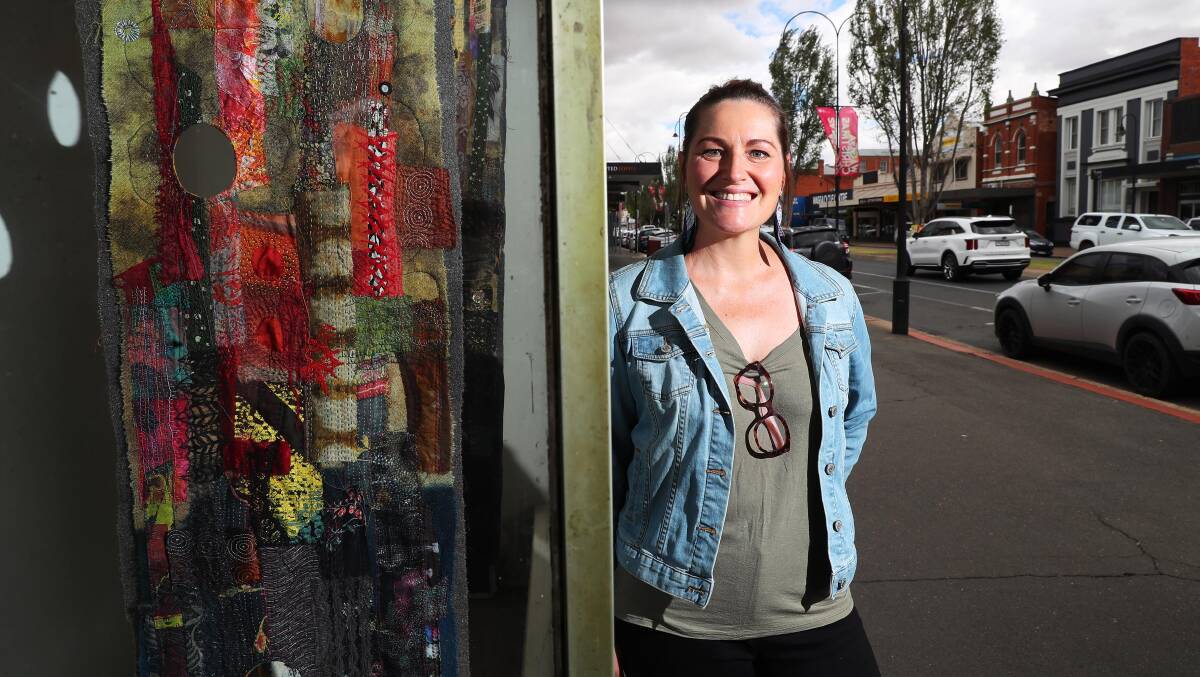 REJUVENATE: Claire Harris shows off artwork by Dr Julie Montgarrett, titled Tensions of Place: once wild country, in the Eastern Riverina Arts building window. Picture: Emma Hillier