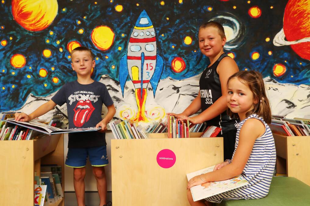 PAGE-TURNER: Local Wagga siblings Huw, 6 (left), Nicholas, 10, and Camila Hutchings, 6, enjoy the books on offer at Wagga City Library while they escape the heat. Picture: Emma Hillier