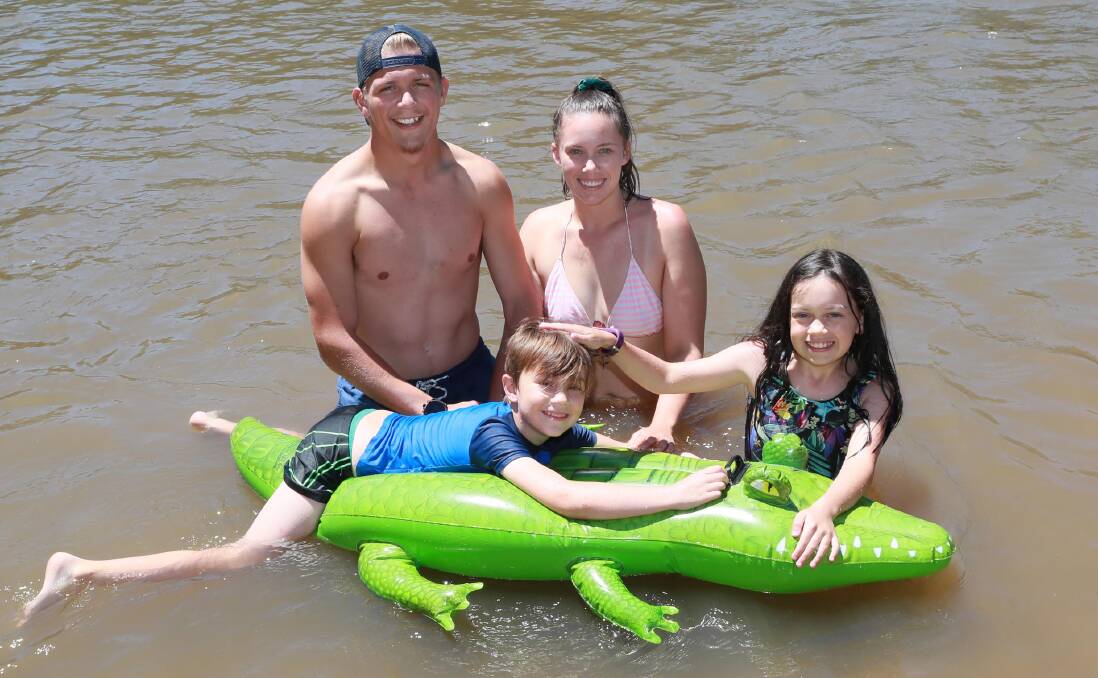STAY COOL: 6-year-old Samuel McPherson with Cobus Cloete, Simone McPherson and Isabel McPherson, 9, enjoy the water at Wagga Beach. Picture: Les Smith