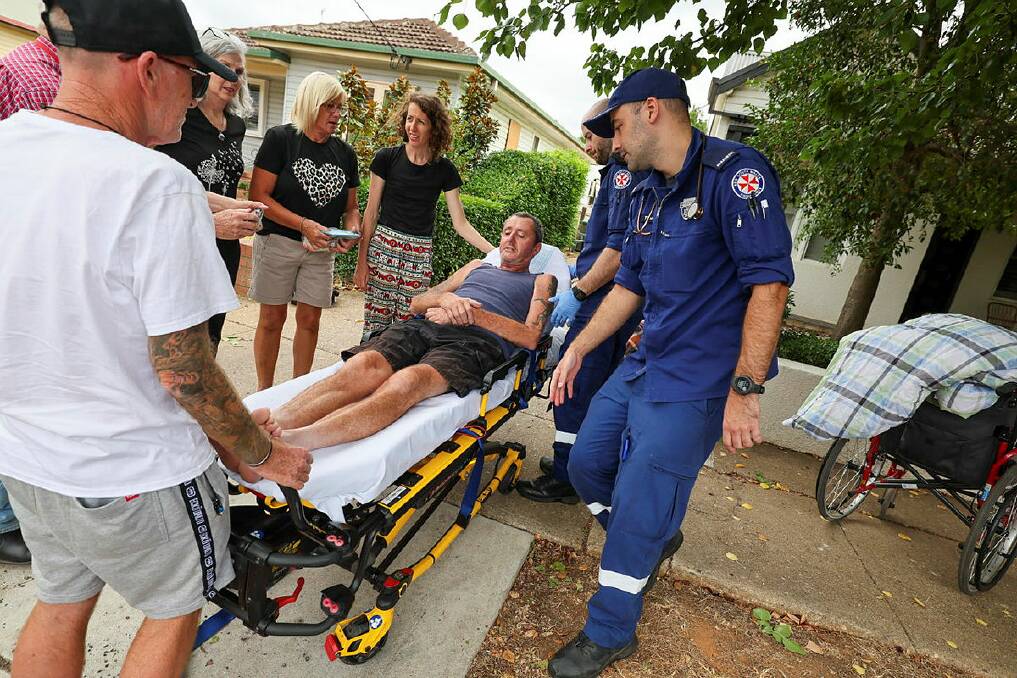 Warren Acott with family and friends as paramedics take him to hospital after he fell from his wheelchair in Wagga last Sunday morning. Picture by Les Smith
