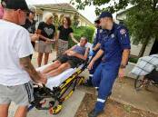 Warren Acott with family and friends as paramedics take him to hospital after he fell from his wheelchair in Wagga last Sunday morning. Picture by Les Smith