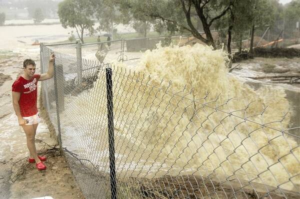 STORMY WEATHER: Luke Doben checks out the incredible sight of water crashing against a stormwater drain at the Wagga Boat Club on Plumpton Road. Picture: Oscar Colman