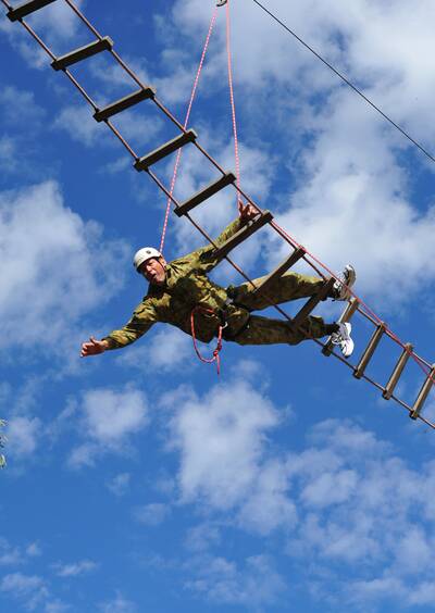 HIGH FLYER: Former Wallabies captain Phil Kearns takes a tumble from the rope bridge before recovering to complete the VIP Challenge obstacle course at Kapooka Army Base yesterday. 	Picture: Addison Hamitlon