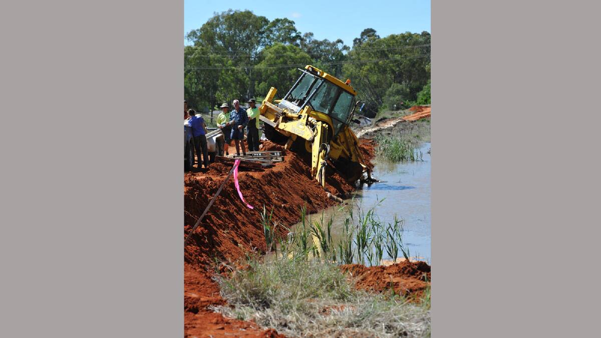 Emergency services repair a lower section of the canal bank in Narrandera but almost lost a backhoe in the process. Picture: Michael Frogley