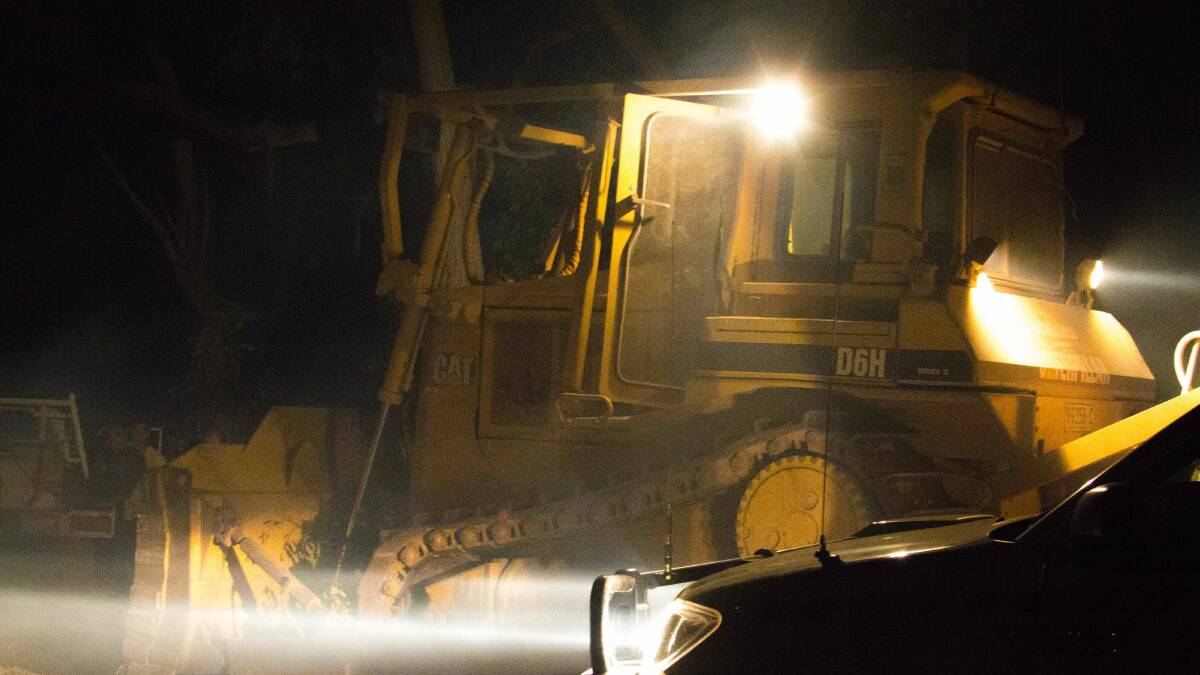 A grader helps build containment lines. Picture: Andrew Roberts