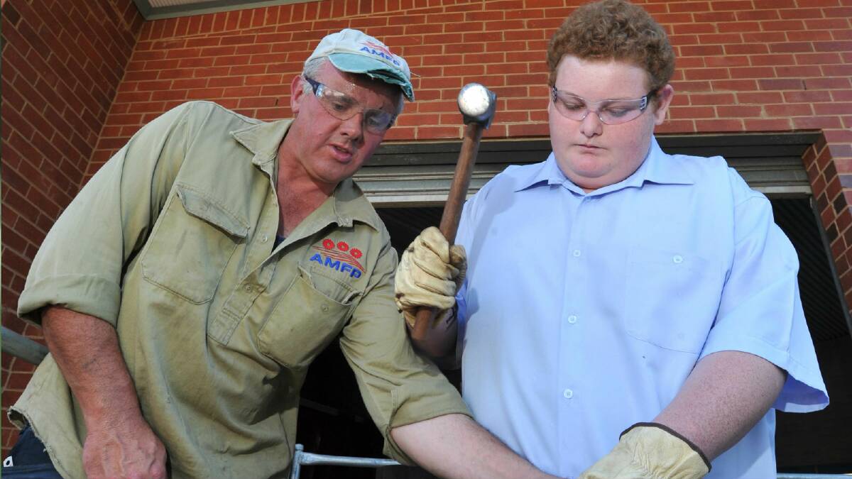 Democratic Labor Party senator John Madigan teaches Wagga High School student Ryan Mitchell, 15, the skill of blacksmithing yesterday. Picture: Les Smith