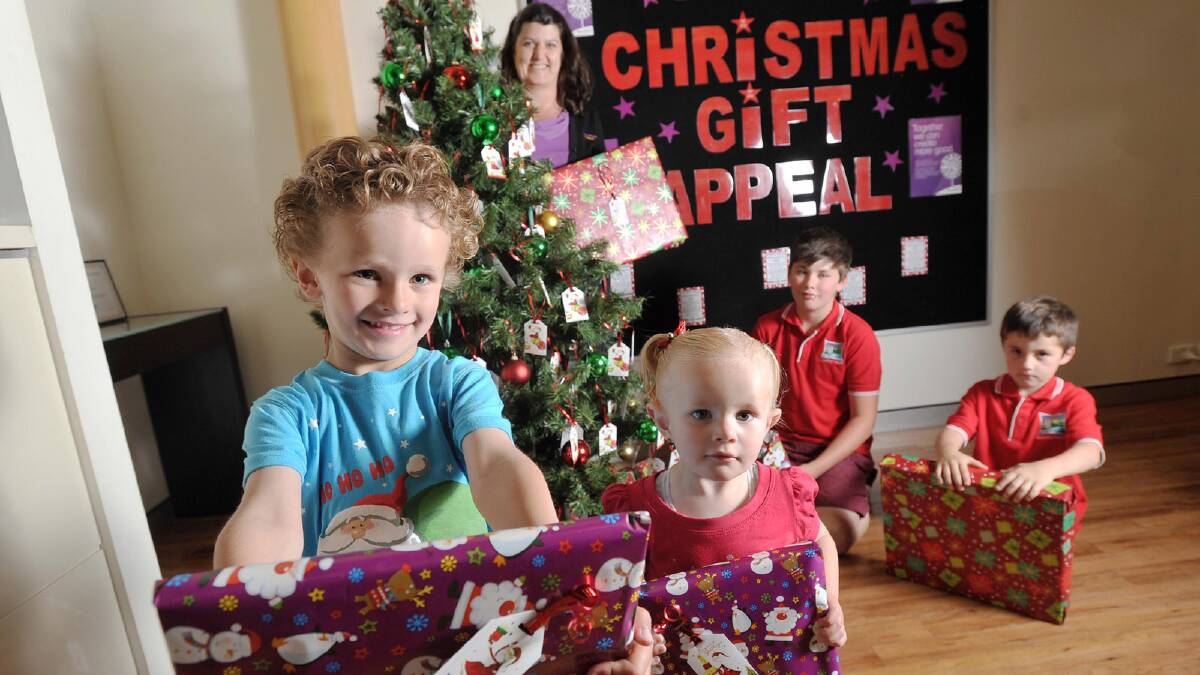 Beyond Bank community coordinator Karen Garrod (back) watches on as Caleb, 5, and Emily, 1, Kearnes (front) join 11-year-old Will Shoemark and five-year-old Braydan Rutland to check out some of the donations under the Christmas tree. Picture: Alastair Brook