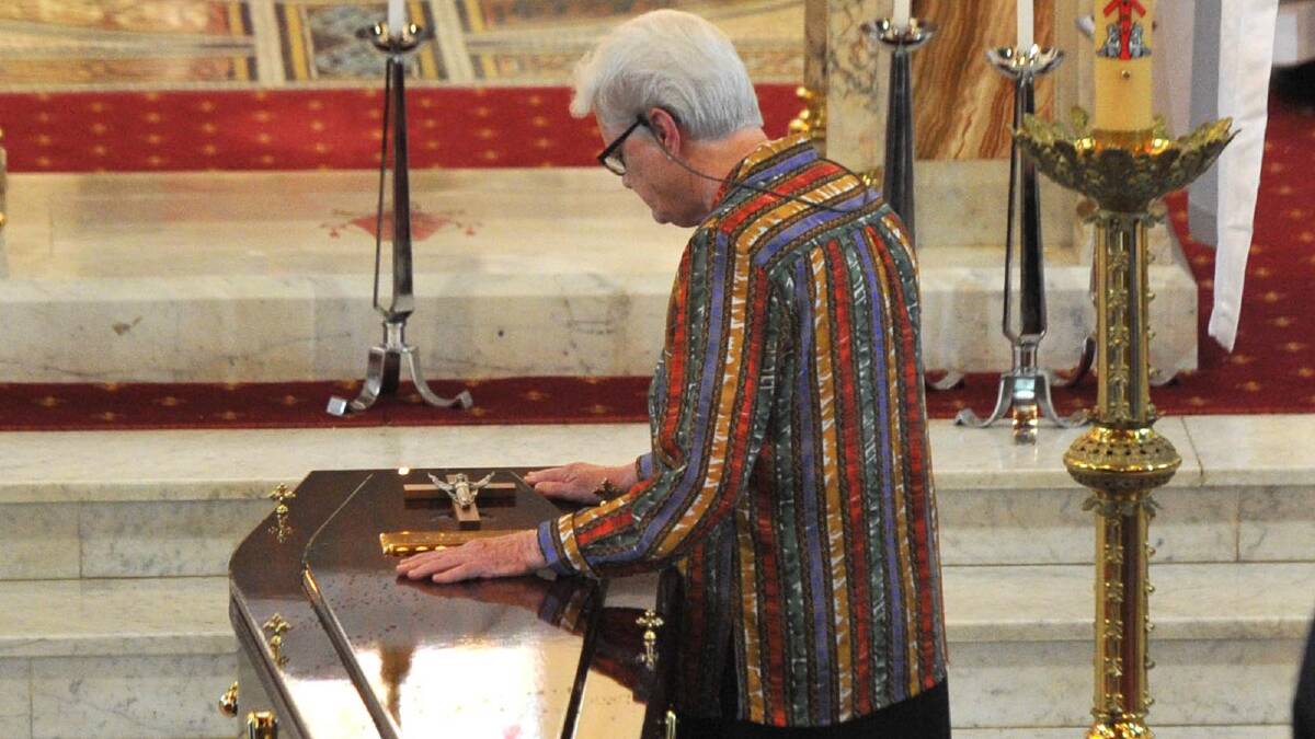 CLOSE: Sister Joan Brennan OSU, younger sister of Bishop William Brennan, places a crucifix on the coffin of her brother, the fourth Bishop of Wagga, at his mass of Christian Burial yesterday. 
